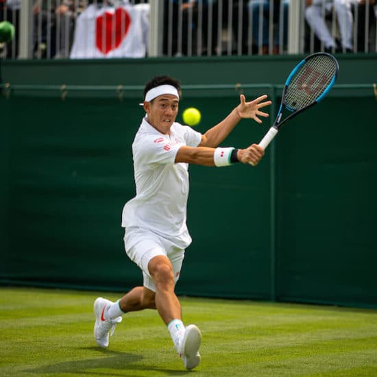 Kei Nishikori of Japan plays a backhand at Wimbledon 2019